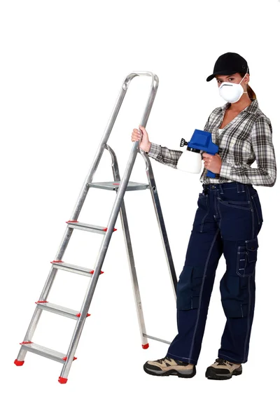 Donna in piedi dalla scala che tiene vernice spray Immagini Stock Royalty Free