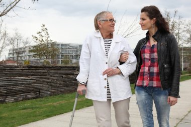 Woman strolling with an elderly lady clipart