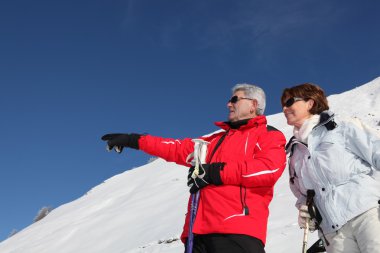 Mature ski couple on a mountain clipart