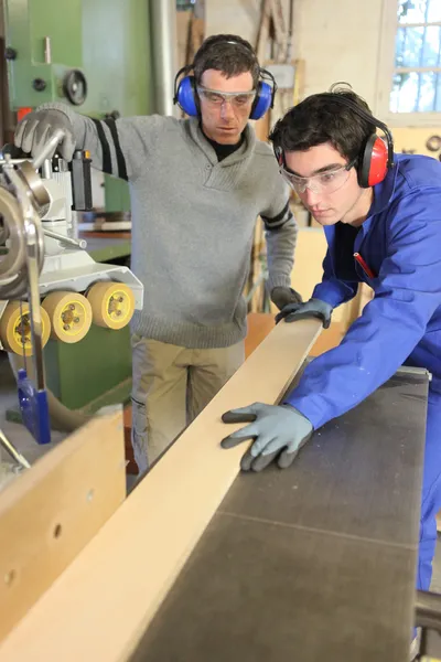 Carpinteiros cortando uma tábua de madeira — Fotografia de Stock