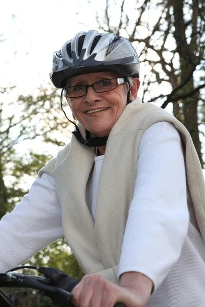 Улыбающаяся пожилая женщина на велосипеде — стоковое фото