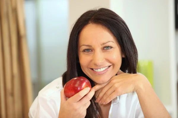 Жінка тримає яблуко з яскравою посмішкою — стокове фото