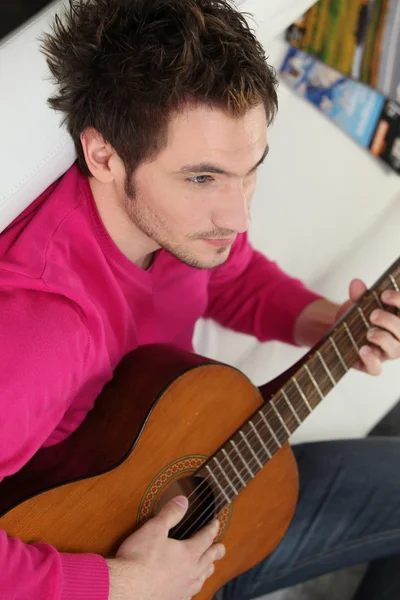 Fiatal ember játszik a gitárján otthon — Stock Fotó