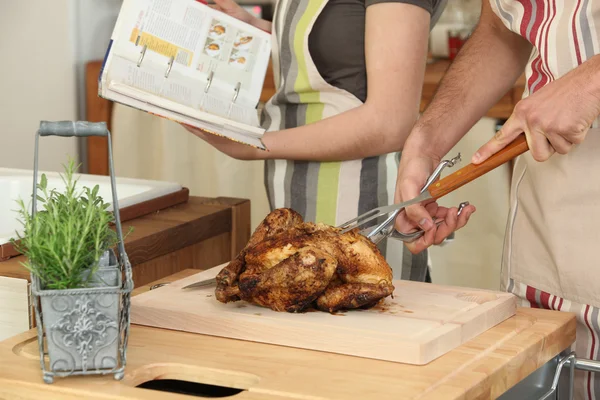 Pareja cocinando un pollo asado —  Fotos de Stock