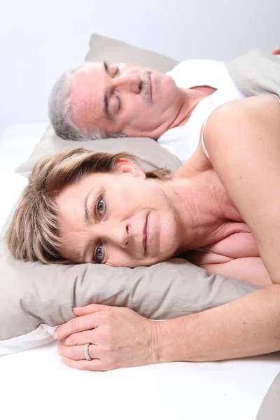 Зрелая пара, лежащая в постели — стоковое фото