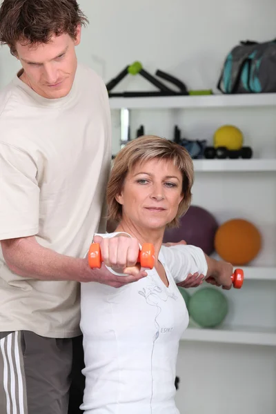 Mulher usando halteres com um personal trainer — Fotografia de Stock
