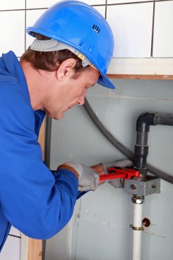 Man installing water pipes with a large wrench clipart
