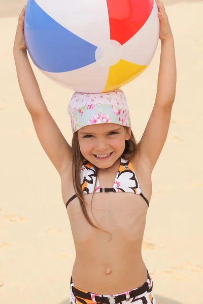 Little at the beach holding inflatable ball above head — Stock Photo, Image