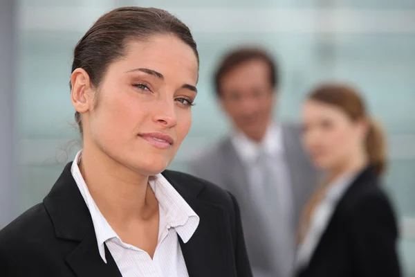 Affärskvinna stod med kollegor i bakgrunden — Stockfoto