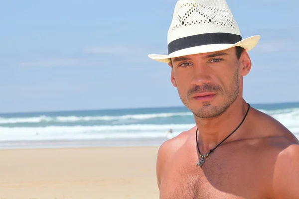 Cara em um chapéu de palha em uma praia ensolarada — Fotografia de Stock