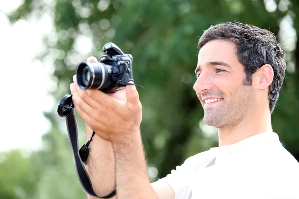 Ευτυχισμένος χαλαρή άνθρωπος ψάχνει στην οθόνη της φωτογραφικής μηχανής του dslr, όπως ο ίδιος παίρνει ένα ph — Φωτογραφία Αρχείου