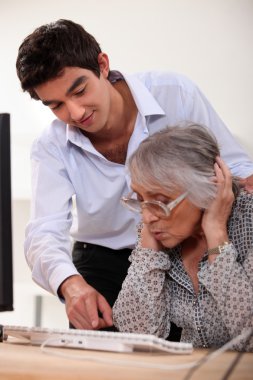 Grandson learning his grandmother haw to use a computer clipart