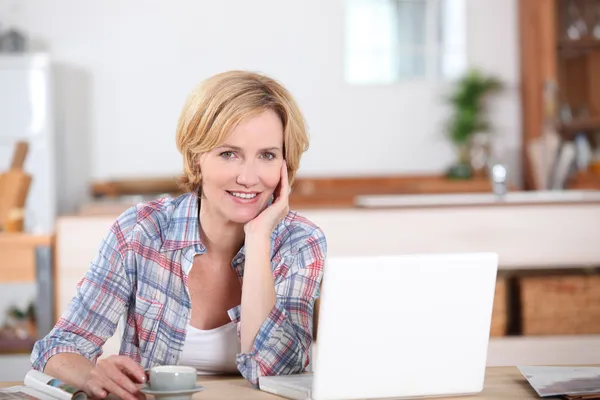 Frau schaut beim Kaffeetrinken auf ihren Laptop — Stockfoto