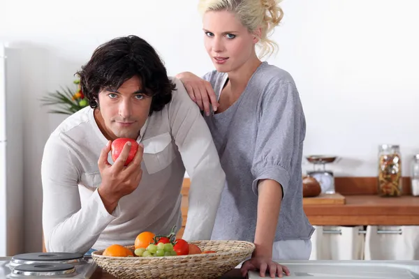 Ένα ζευγάρι στην κουζίνα, ο άνθρωπος τρώει ένα μήλο — Φωτογραφία Αρχείου