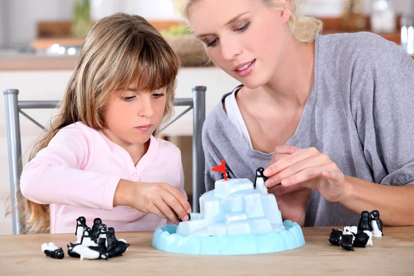 Mother an daughters playing with small penguins figurines — Stock Photo, Image
