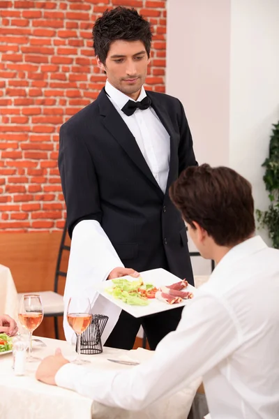 Официант, подающий еду в ресторане — стоковое фото