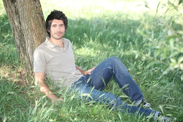 Uomo nel parco seduto vicino all'albero — Foto Stock