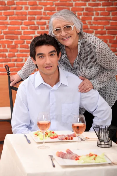 A young man and an old woman at the restaurant posing for the camera — Stock Photo, Image