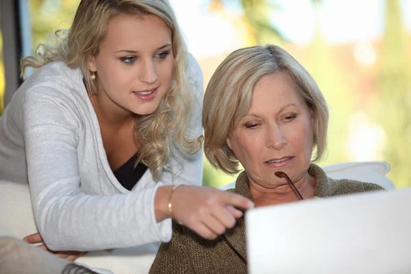 Granddaughter showing her grandmother how to use a computer — Stockfoto