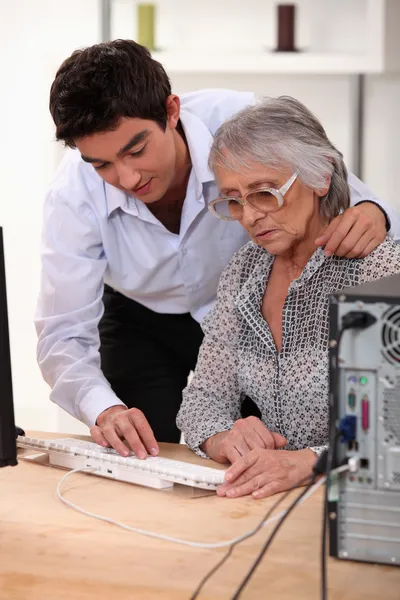 Внук показывает бабушке, как пользоваться компьютером — стоковое фото