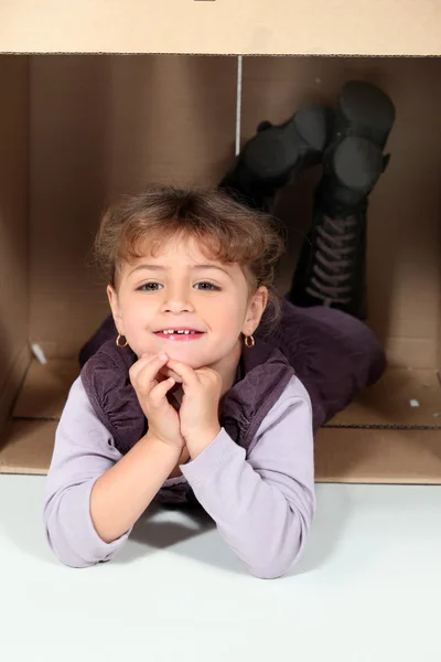 Bambina sdraiata in una scatola di cartone — Foto Stock