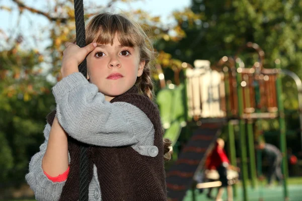 Chica sosteniendo una cuerda en un patio de recreo —  Fotos de Stock