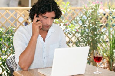 Man speaking on his mobile phone while drinking wine and surfing the Net on clipart