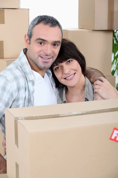 Um casal na frente de uma pilha de caixas — Fotografia de Stock
