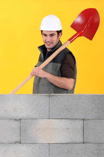 Worker stood by wall with spade — Stock Photo, Image