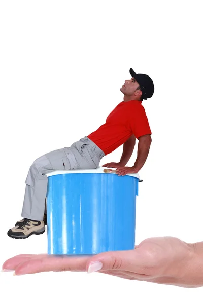 Trabalhador com tampa sentada na lata de tinta — Fotografia de Stock