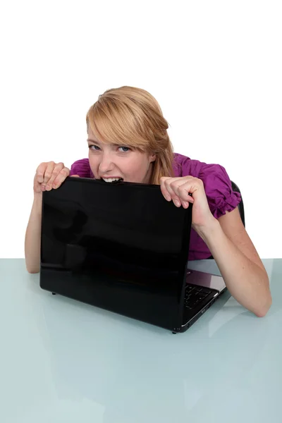 Young woman biting her laptop — Stock Photo, Image