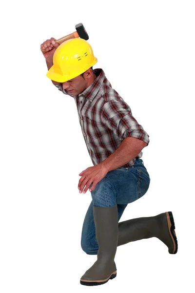 Un falegname inginocchiato con un martello . — Foto Stock