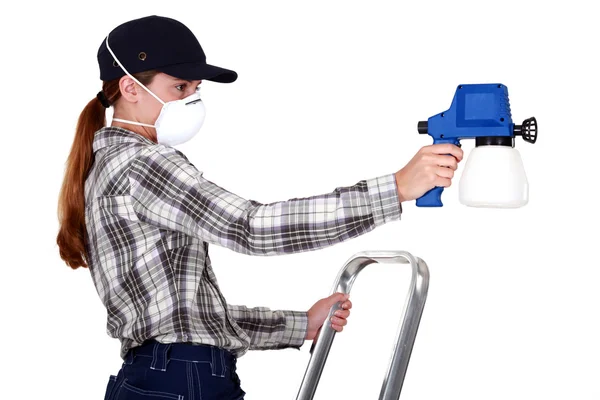 Kvinna som bär en mask för att använda en spraygun — Stockfoto