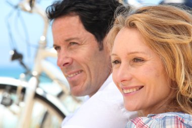 Headshot of couple with bikes by the sea clipart