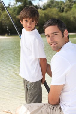 Father and son fishing at a lake clipart