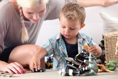 Mother and child playing with toy cars clipart
