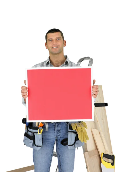 Строитель держит красную доску объявлений — стоковое фото
