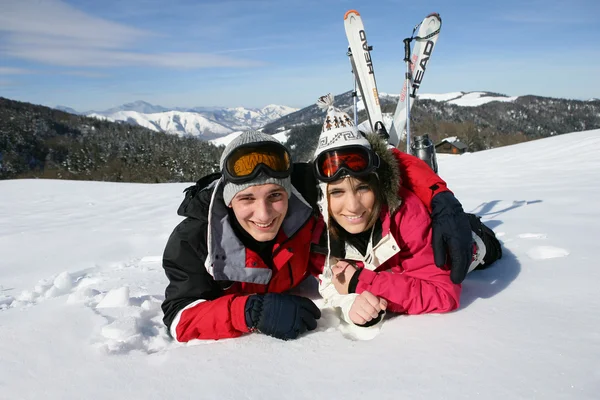 Gelukkige jongen en meisje liggen in de sneeuw — Stockfoto