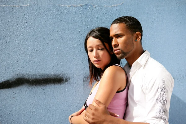 Teens embracing in front of a wall — Stock Photo, Image