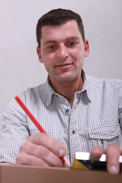 Fechamento de um homem desenhando uma linha em um pedaço de madeira — Fotografia de Stock