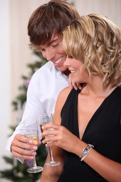 Par dricka champagne framför en julgran — Stockfoto