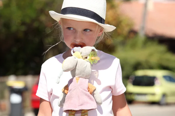 Маленька дівчинка в солом'яному капелюсі з лялькою та іграшковим кроликом — стокове фото