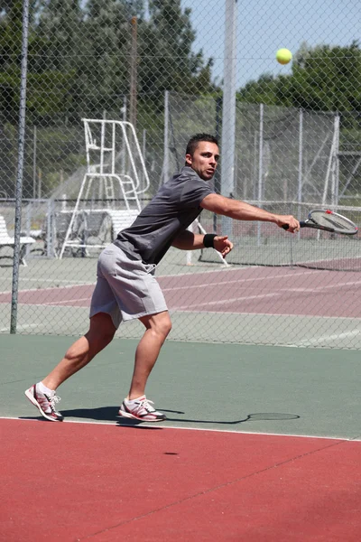 Мужчина играет в теннис на жестком корте — стоковое фото