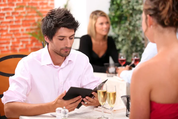 Junger Mann schaut sich Speisekarte in Restaurant an — Stockfoto