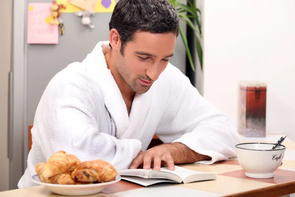 Przystojny mężczyzna, czytając książkę na śniadanie — Zdjęcie stockowe