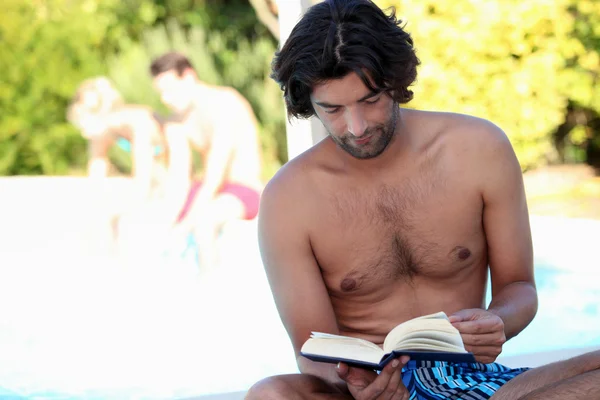 Άνθρωπος ανάγνωση δίπλα στην πισίνα — Φωτογραφία Αρχείου