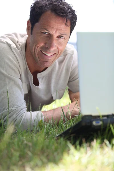 Uomo sorridente che lavora sull'erba — Foto Stock