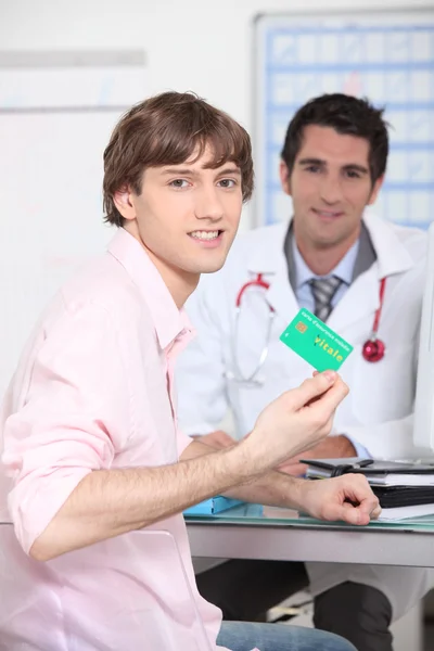 Mladý člověk ukazuje své francouzské zdravotní pojištění karty — Stock fotografie