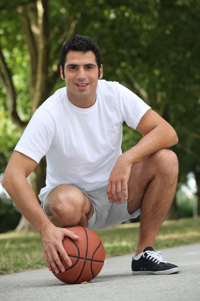 Man crouching met mand bal — Stockfoto