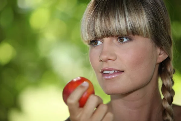 Una mujer rubia comiendo una manzana —  Fotos de Stock